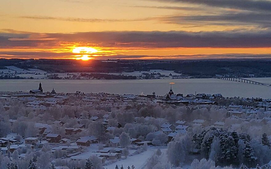 Wiesen und Häuser im Schnee bei Sonnenuntergang