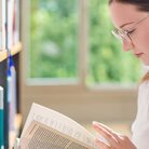 Studentin liest in Buch in der Bibliothek