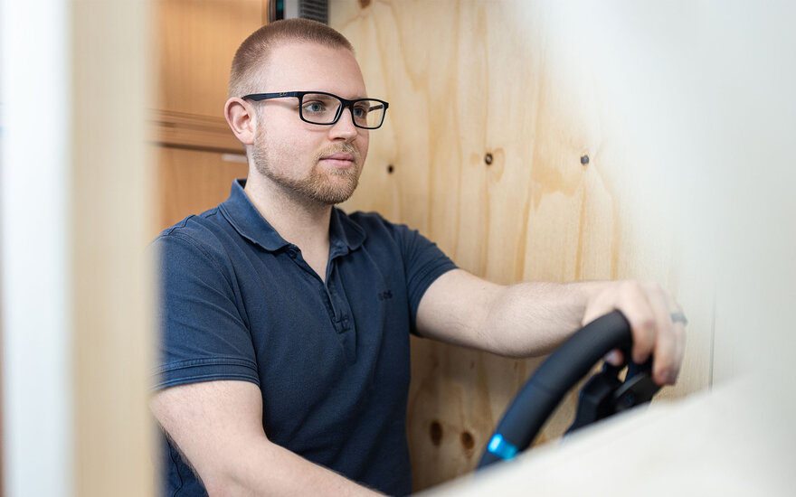 Labormitarbeiter testet am stationären Fahrsimulator für Fahrerforschung