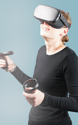 Eine Frau mit VR-Brille und Joysticks.