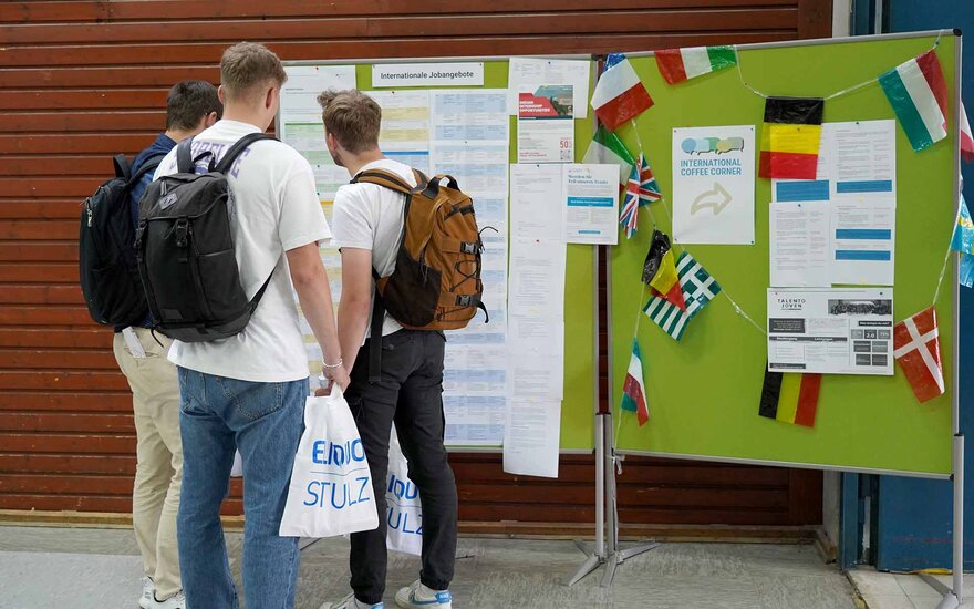 Drei junge Männer sthen vor grünen Pinnwänden bei den Campus Careers.