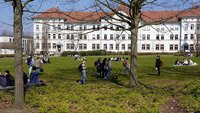 Studierende auf der Campuswiese vor dem Gebäude der Fakultät WR