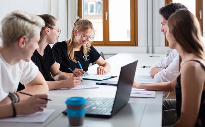 Mehrere Studierende während einer Gruppenarbeit mit Laptop und TH AB To-Go Becher.