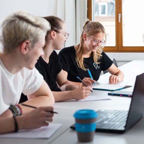 Mehrere Studierende während einer Gruppenarbeit mit Laptop und TH AB To-Go Becher.