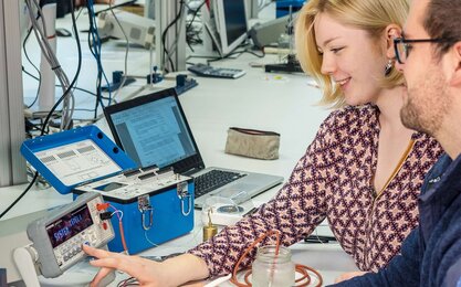 Studierende messen die Wassertemperatur im Glas mit Hilfe eines Thermowiderstands.