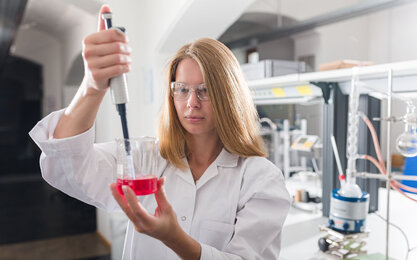 Eine Studentin mit einer Pipette und einem Becherglas mit Flüssigkeit in einem Labor an der TH Aschaffenburg.