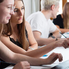 Vier Studierende mit Laptops in Seminarraum von der Seite