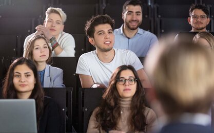 Mehrere Studierende in einem Hörsaal während einer Vorlesung in Frontalansicht