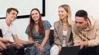 Studierende des Studiengangs SD sitzen mit Laptops und tablets in einem Kreis.