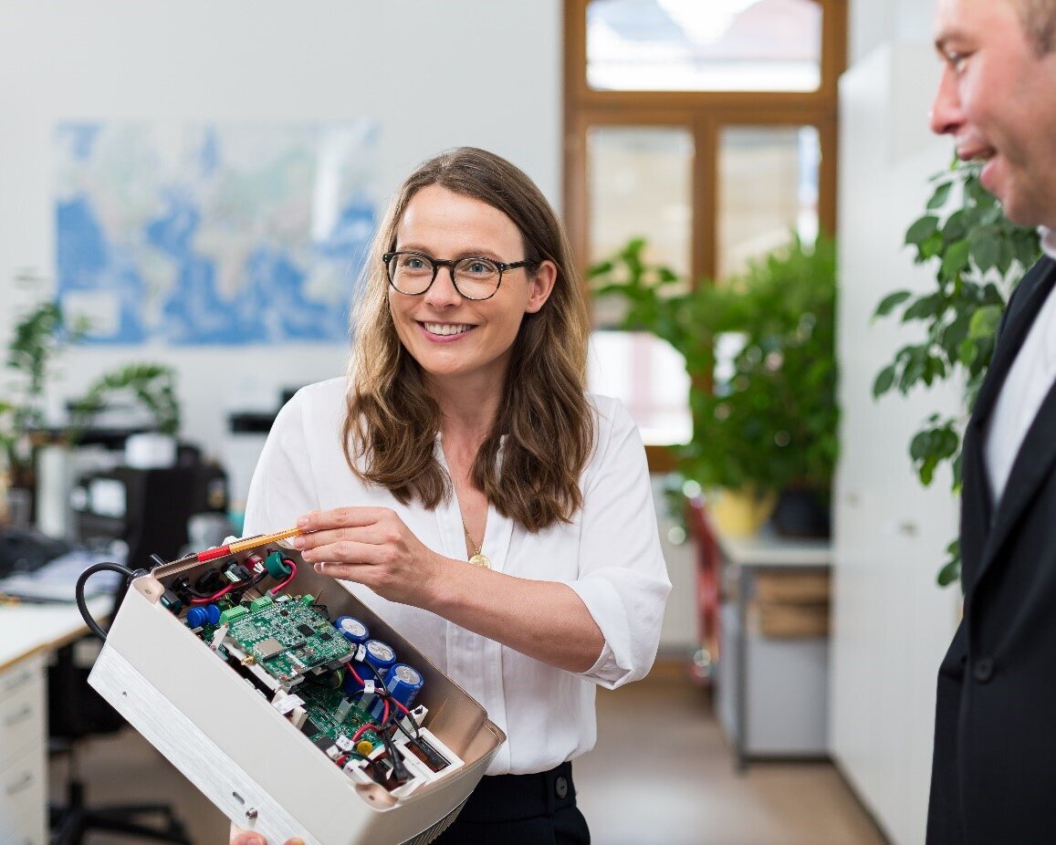 Frau zeigt Mann ein Forschungsprojekt. Im Hintergrund ist ein Büro.