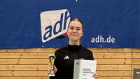 Siegerin Anna Braun mit Urkunde und Pokal in der Hand vor Hochschulverbandsbanner