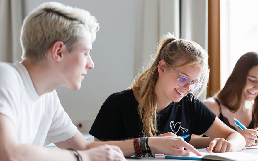 Drei Studierende lernen mit einem Buch