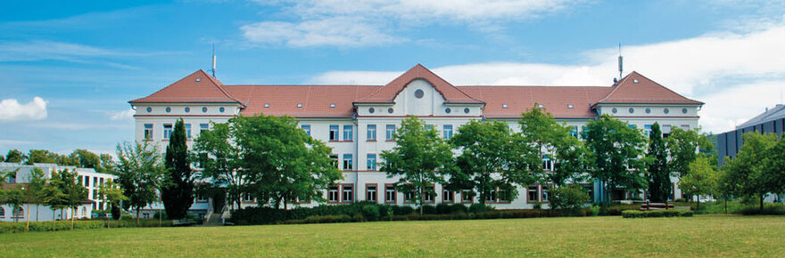 Campus-Wiese und Gebäude 20 am Campus 1 Hochschulgebäude der Technischen Hochschule Aschaffenburg, umgeben von Grünanlagen an einem sonnigen Tag.