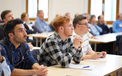 Student*innen sitzen in einem Hörsaal und hören gespannt zu.