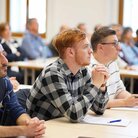 Student*innen sitzen in einem Hörsaal und hören gespannt zu.