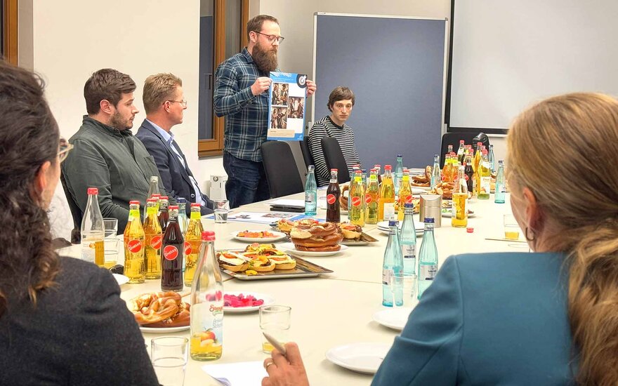 Doktorand Marco Klopp präsentiert ein Poster mit den Inhalten seiner Promotion.