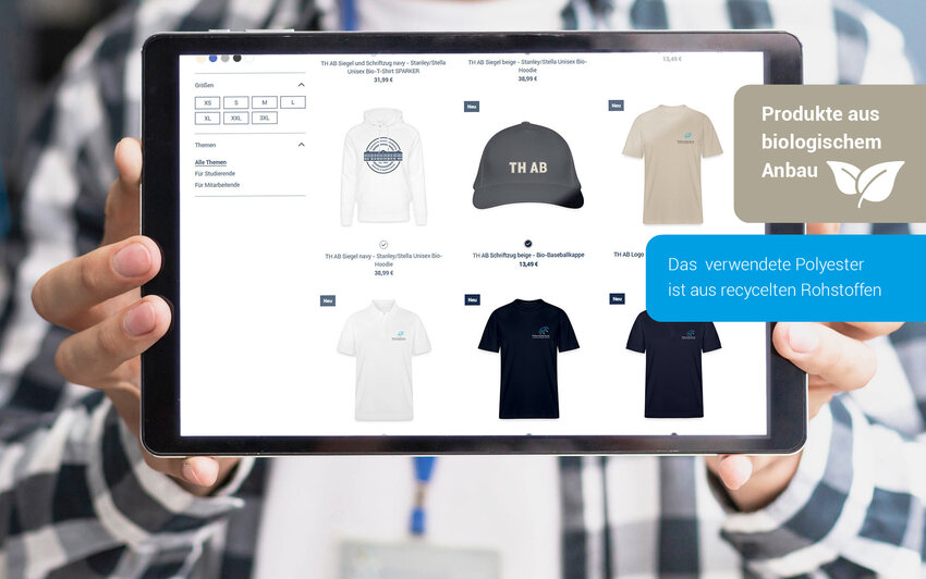 Hände halten Tablet in die Kamera, auf dem Bildschirm ist ein Shopbereich mit Shirts, einem Hoodie und einer Kappe zu sehen