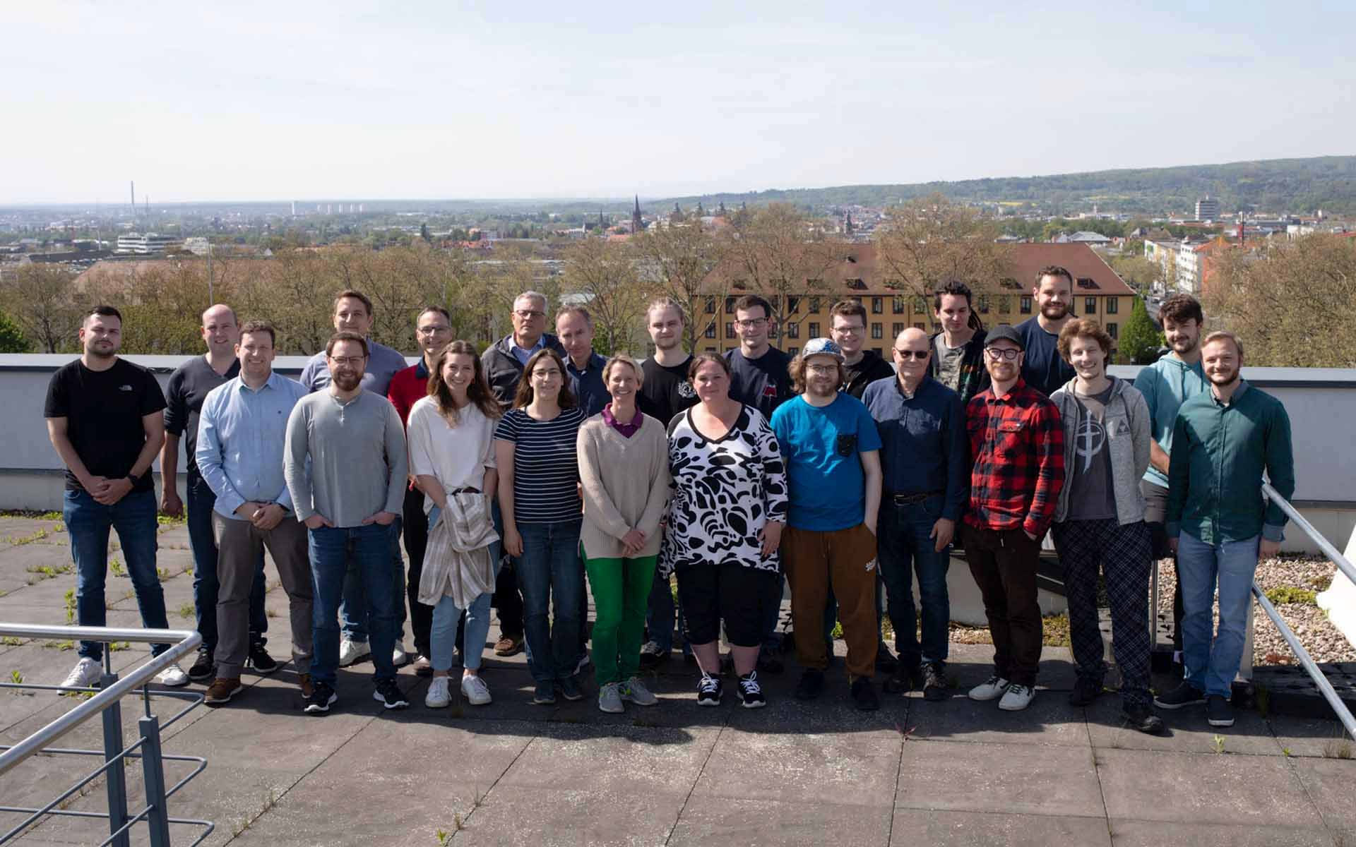 Gruppenfoto mit allen Teammitglieder unter freiem Himmel mit dem Stadtpanorama von Aschaffenburg im Hintergrund