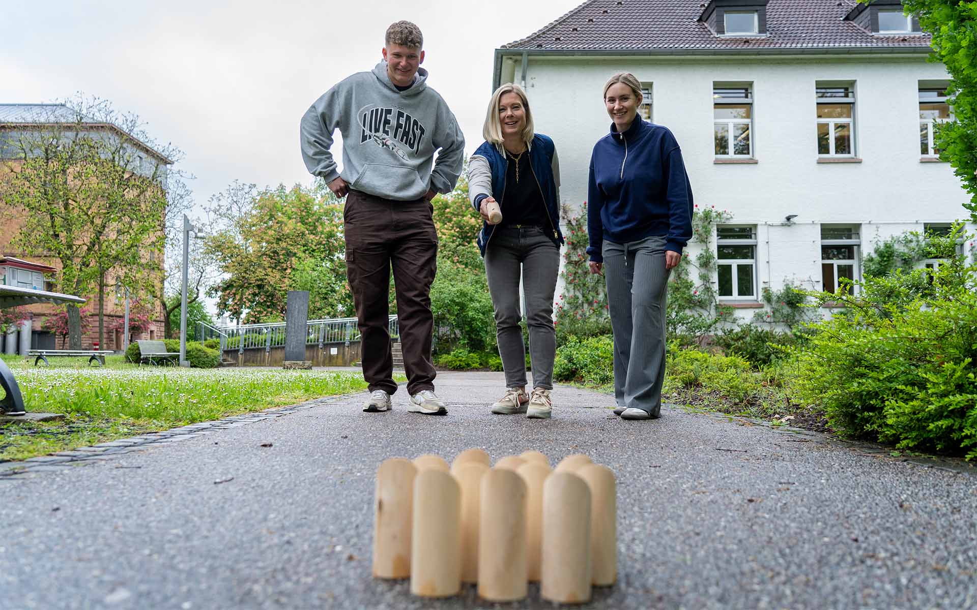 Drei Menschen spielen auf dem Campus ein Spiel.