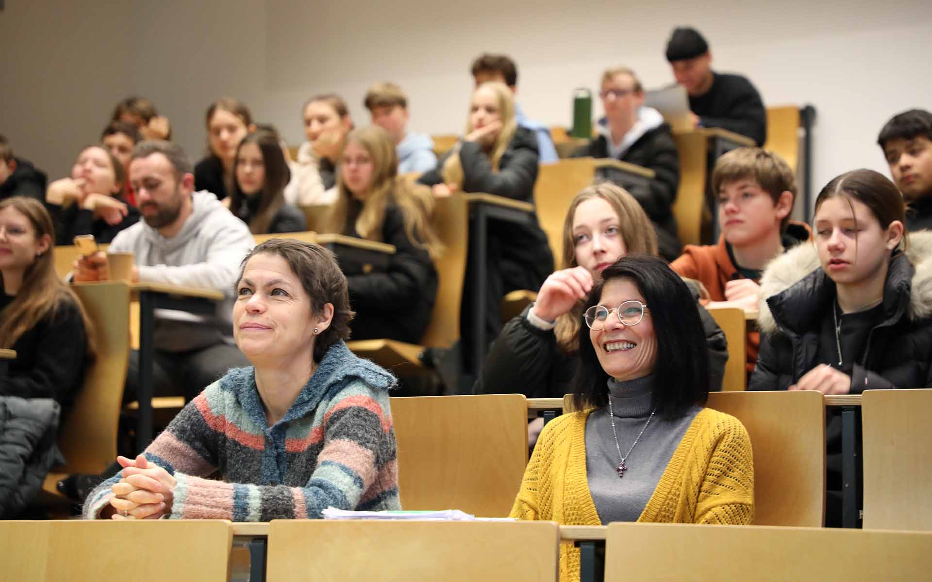 Schülerinnen und Schüler sitzen in einem Hörsaal mit ansteigenden Tischreihen